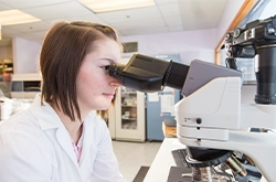 Lab tech looking through microscope