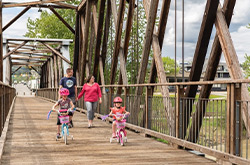 Family walking and biking across the bridge in Quesnel