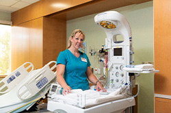 Female nurse standing beside nicu bed