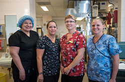 Four smiling staff wearing uniforms