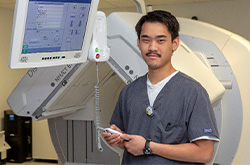Male nurse standing in front of a machine.